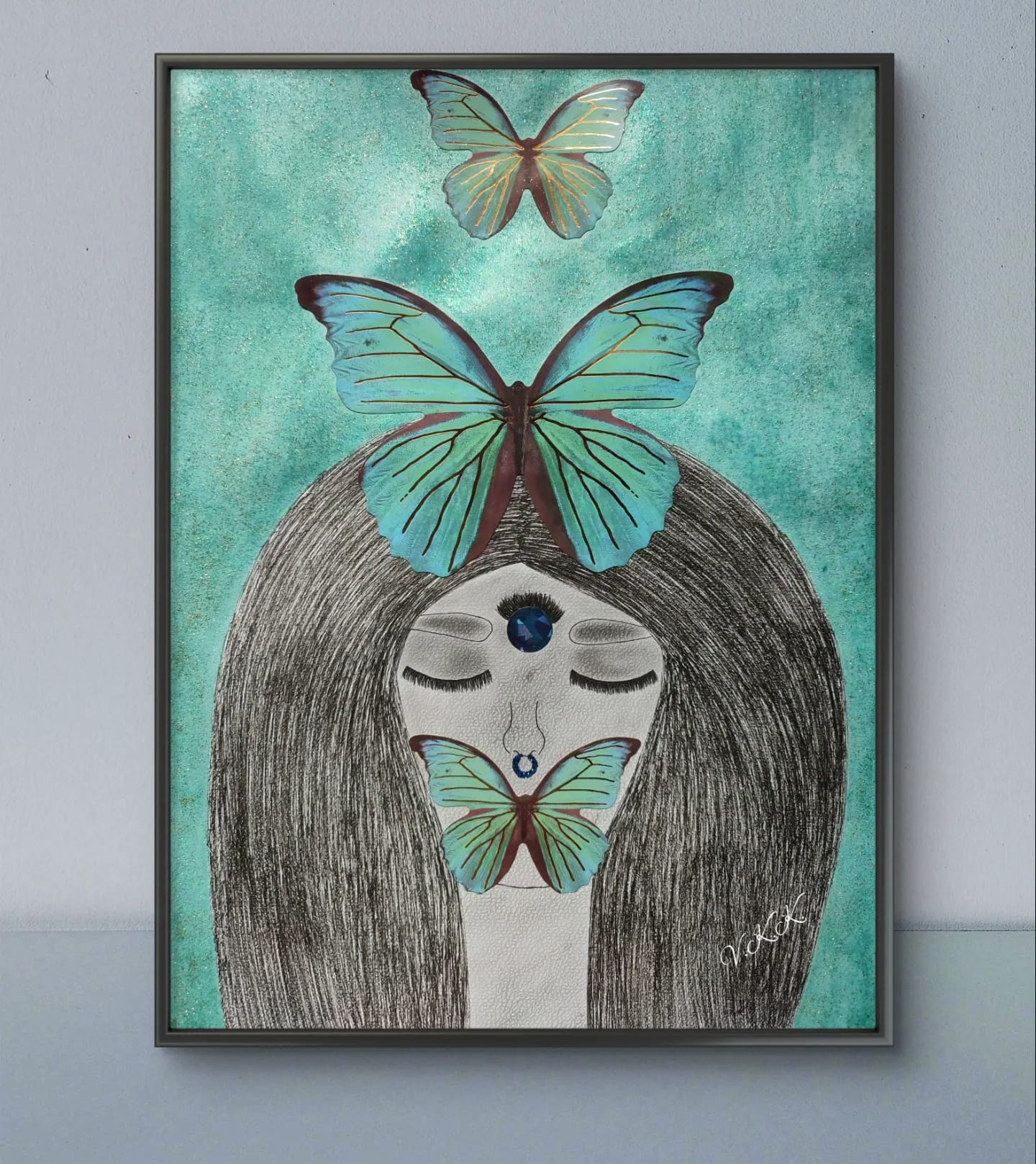 Framed artwork of a woman with closed eyes and blue gem, surrounded by teal butterflies.