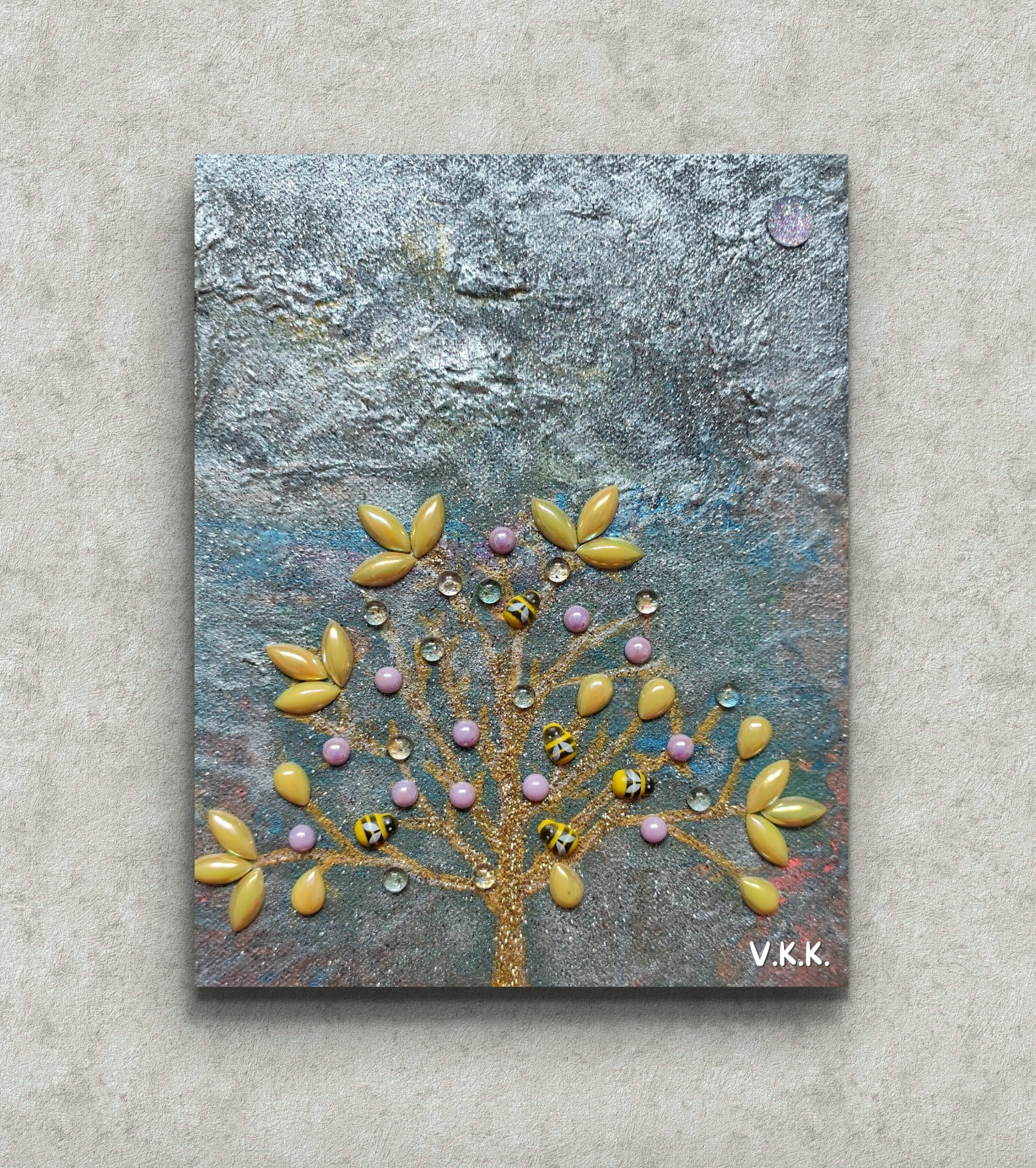 Decorative wall art panel with a glittering tree, yellow petals, pink beads, and small bee figurines.